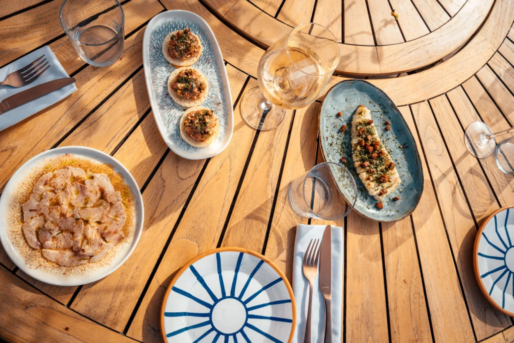 Platos en la mesa: tartar de ternera, calamares con perejil y chorizo, y carpaccio de dorada 