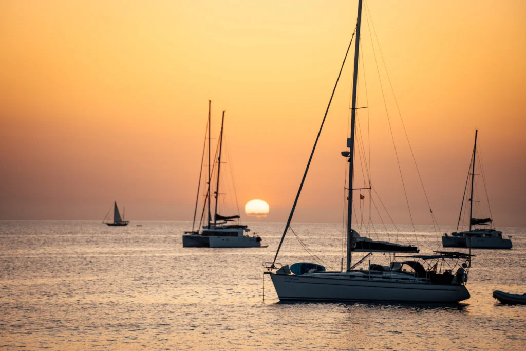 Foto del panorama dal Monkey Ibiza, con vista sul mare al tramonto. All'orizzonte si scorgono diverse barche a vela