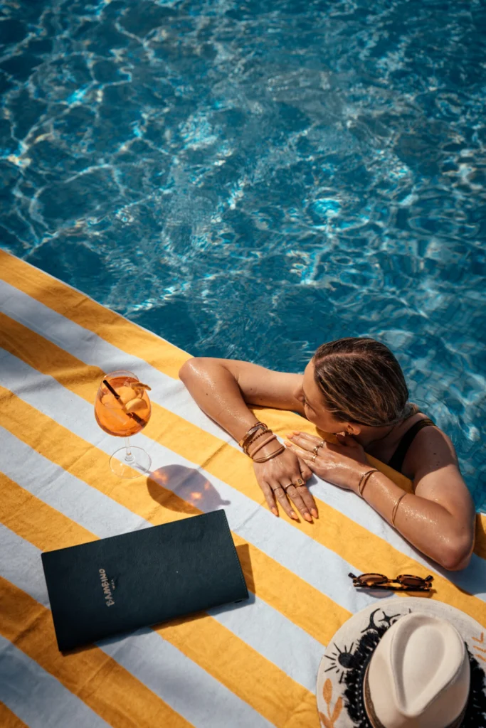 Foto de una mujer apoyada en el borde de la piscina del Bambino Pool Club